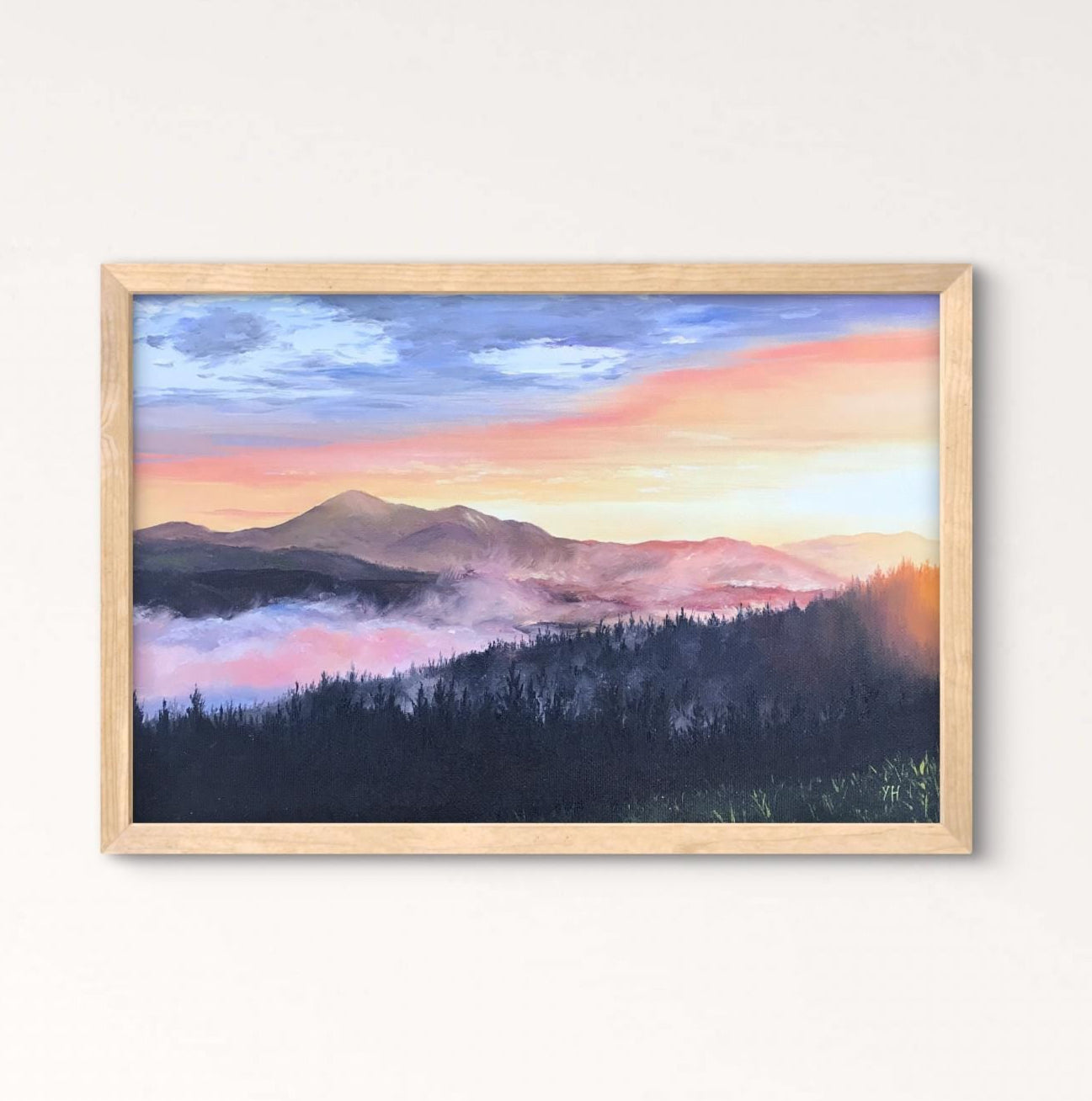 Framed landscape painting above a wooden table with a vase of dried flowers.