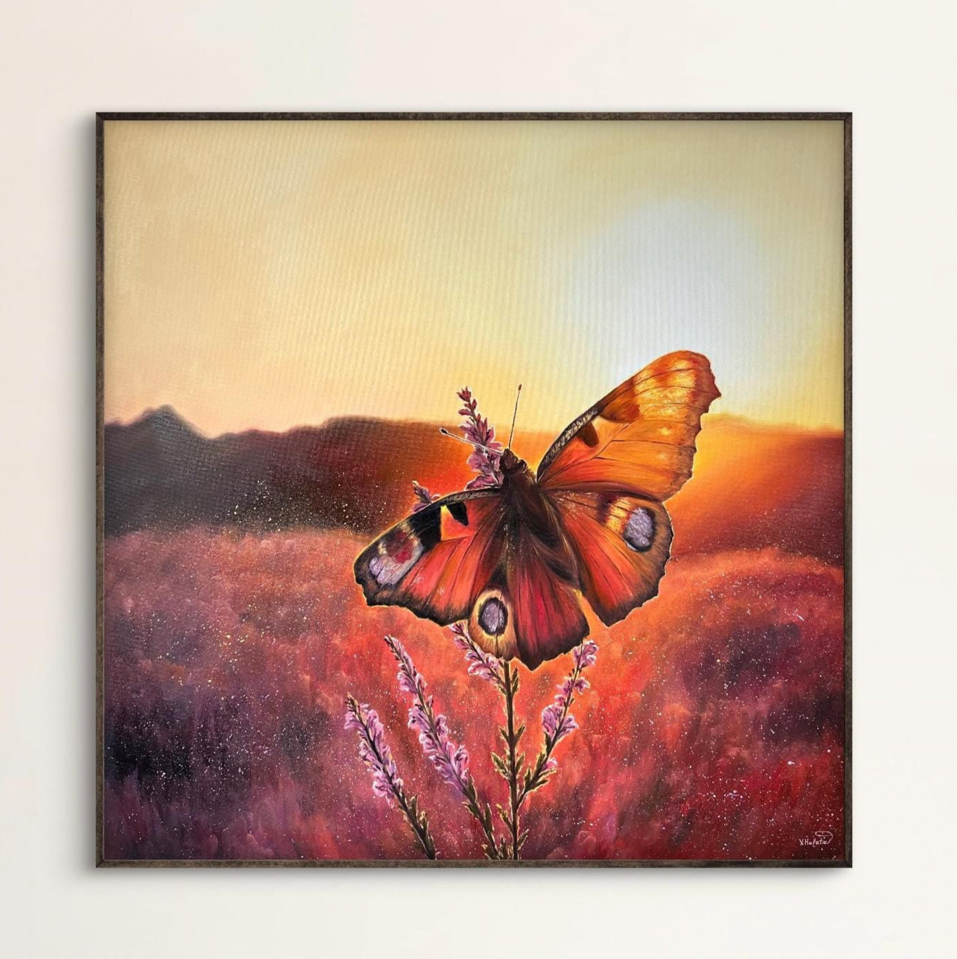 Framed artwork of a butterfly on a flower with a sunset background