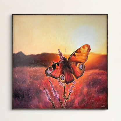 Framed artwork of a butterfly on a flower with a sunset background