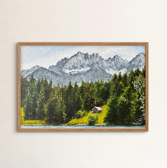Framed painting of a mountain landscape with a cabin.