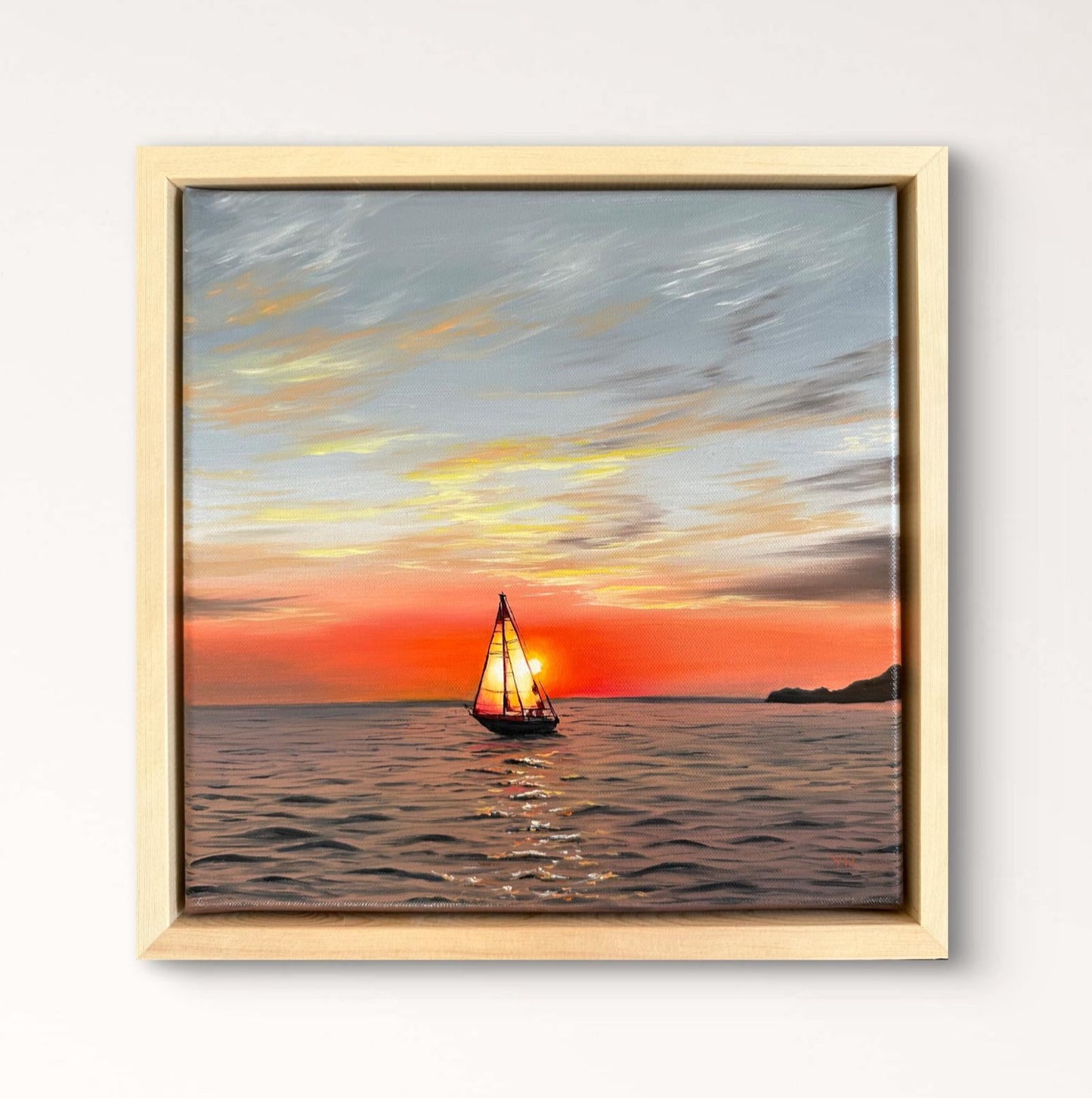 Framed artwork of a sunset with a sailboat above a wooden console table.