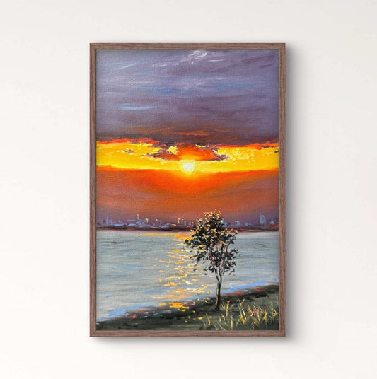 Framed artwork of a sunset over water on a wall above a wooden console table with a vase.