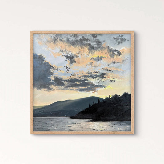 Framed artwork of a landscape with a lake and mountains on a white wall.