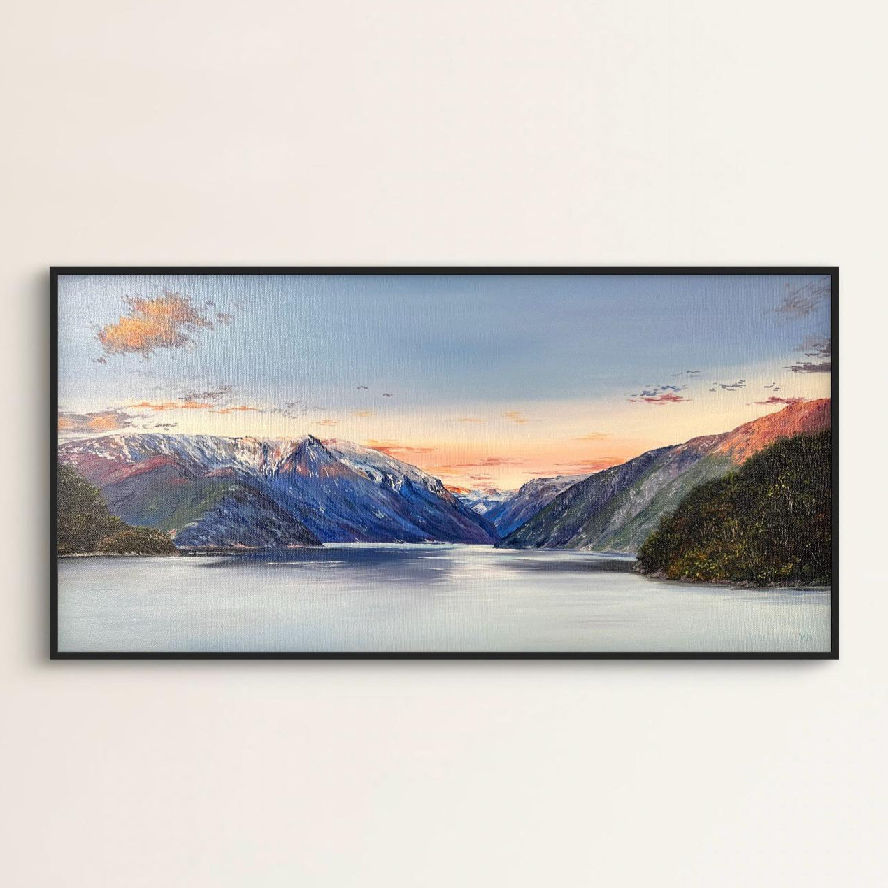Framed artwork of a mountain landscape with a lake on a white wall