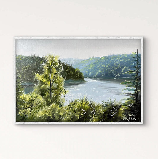 Framed painting of a landscape with trees and a river on a white wall.