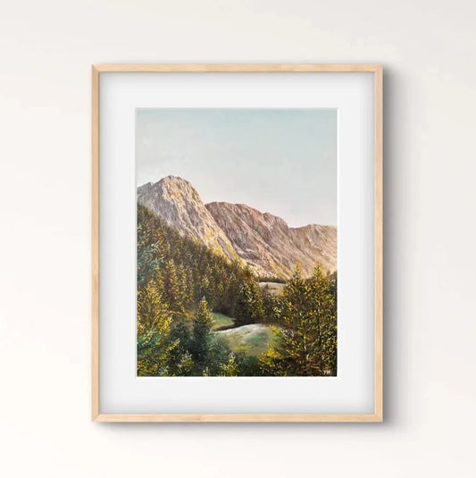 Framed landscape print on a wall above a wooden console table with a vase.